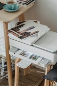 photos placed on printer near table with cup of coffee