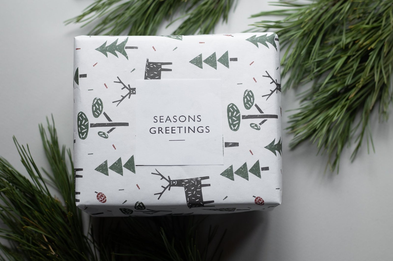 gift wrapped in festive paper with trees and deer between green tree branches